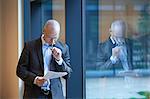 Mature businessman by office window reading paperwork