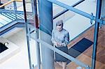 High angle view of businesswoman looking at smartphone on office stairway