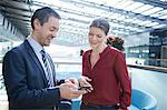 Businessman and woman looking at smartphone in office atrium