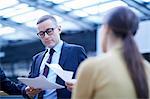 Businessman and woman reading paperwork in office