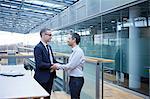 Two businessmen shaking hands on office balcony