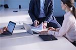 Businesswoman and men using laptops boardroom table