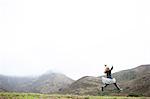 Landscape view of girl in tutu jumping mid air