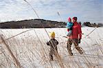 Father walking with two sons in snow covered landscape