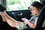 Young boy sitting in child's seat in back seat of car, bored expression