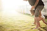 Father and son fooling around outdoors, young boy walking between father's legs