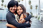 Portrait of mother and daughter hugging looking at camera