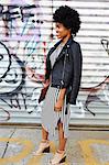 Young female fashion blogger with afro hair by graffiti wall, New York, USA