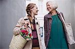 Smiling mother and daughter with shopping bags in alley