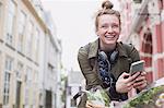 Portrait enthusiastic young woman on bicycle texting on city street