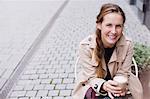 Portrait smiling woman drinking iced coffee at sidewalk cafe