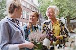 Florist showing plants to mother and daughter at storefront