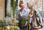 Florist showing flowers to female shopper at storefront