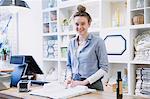 Portrait smiling female cashier wrapping merchandise at checkout counter