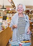 Portrait smiling female shopper with basket in shop
