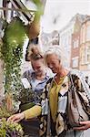 Female florist helping woman shopping for potted plants at storefront