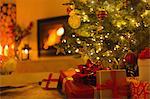 Gifts under Christmas tree in ambient living room with fireplace