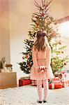 Girl in pink dress holding Christmas gift in front of Christmas tree