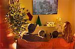 Family watching TV in Christmas living room