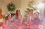 Family wearing paper crowns at Christmas dinner table