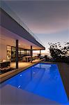 Tranquil blue lap swimming pool outside modern luxury home showcase exterior