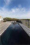 Dark luxury swimming pool under sunny blue sky