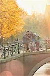 Friends taking selfie with selfie stick on autumn bridge over canal in Amsterdam