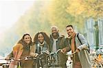 Portrait smiling friends bike riding on urban autumn street