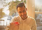 Personal perspective young man giving gift in sunny cafe