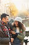 Affectionate couple hugging along autumn canal