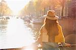 Woman looking at sunny autumn canal view, Amsterdam