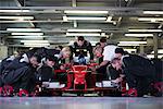 Pit crew preparing formula one race car and driver in repair garage