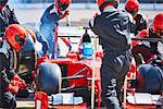 Pit crew working on formula one race car in pit lane