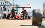 Pit crew working on formula one race car in pit lane