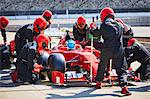 Pit crew working on formula one race car in pit lane