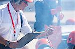 Manager with clipboard and stopwatch timing  formula one pit crew practice session