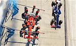 Overhead pit crew replacing tires on formula one race car in pit lane