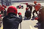 Pit crew ready for nearing formula one race car driver in pit lane