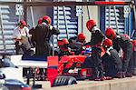 Pit crew replacing tires on formula one race car in pit lane