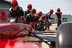 Pit crew with tires ready for nearing formula one race car in pit lane