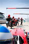 Pit crew with tires ready for nearing formula one race car in pit lane