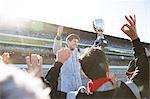 Formula one racing team cheering for driver with trophy, celebrating victory on sports track