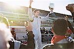 Formula one racing team cheering for driver with trophy, celebrating victory on sports track