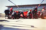 Pit crew replacing tires on formula one race car in pit lane