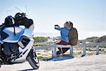 Senior couple taking selfie at sunny roadside near motorcycle