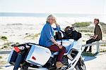 Portrait confident senior woman on motorcycle on sunny beach