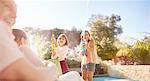 Playful sisters with squirt guns spraying water at sunny summer poolside