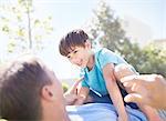 Laughing son laying on top of father on sunny patio