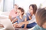 Family using laptop in sunny living room