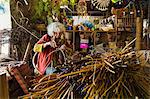 Woman weaving a basket in a weaver's workshop, bundles of willow.